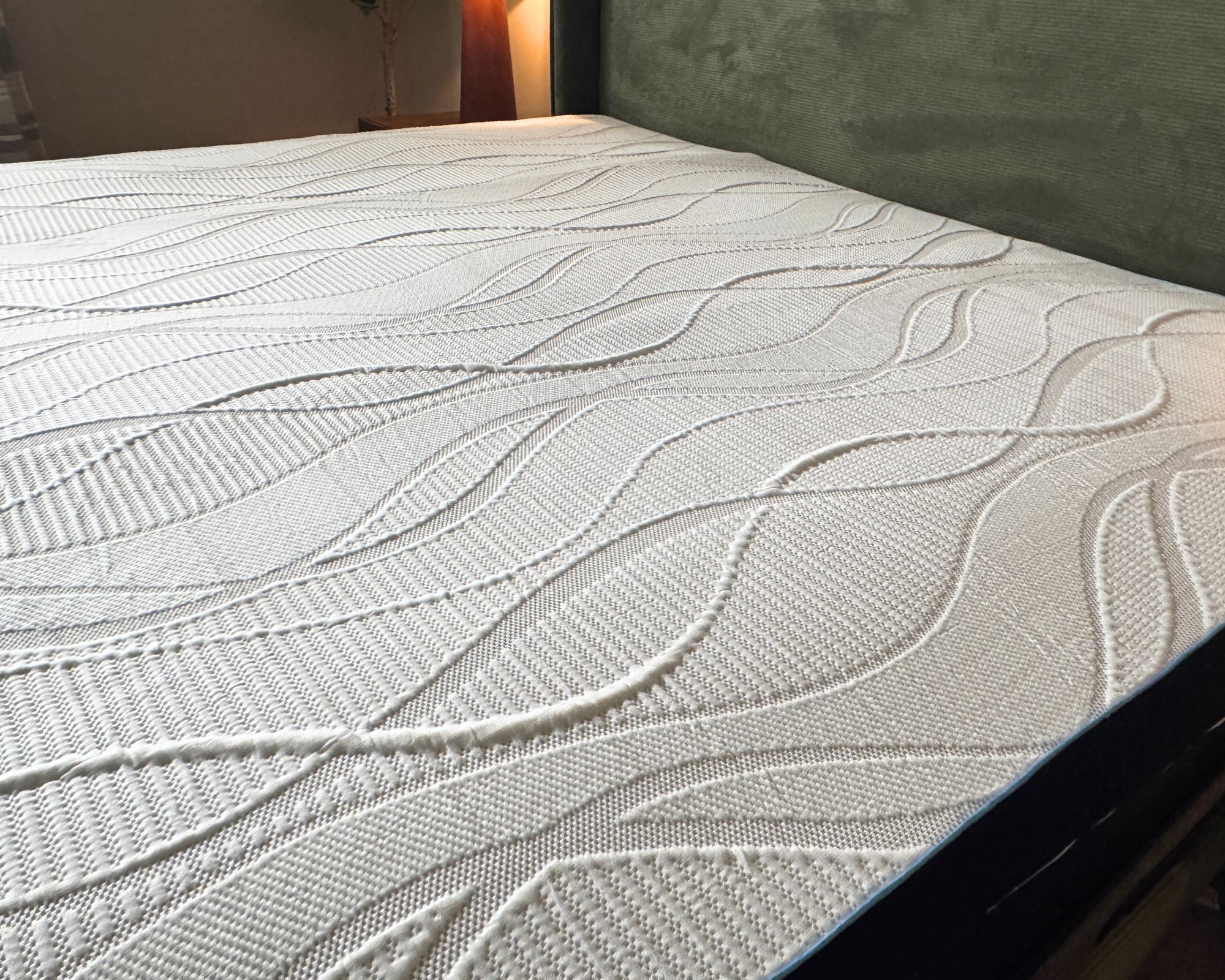 Nectar firmer memory foam topper on a bed with green velvet headboard.