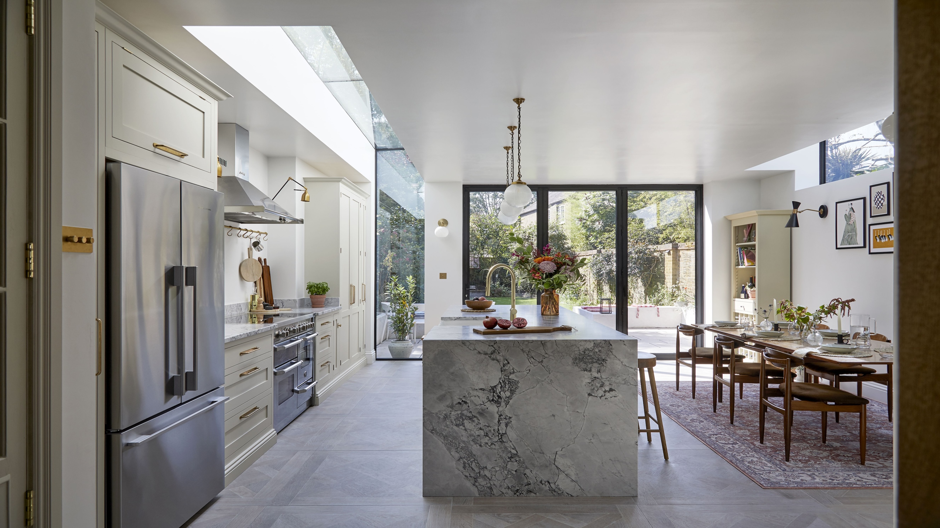 A large kitchen with an island and dining area next to the island. There is also a view of the double door fridge in the kitchen.