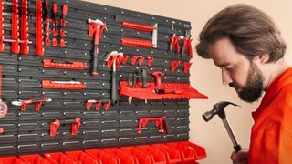 A man in an orange jumpsuit holding a hammer stands in front of a rack of VEVOR tools