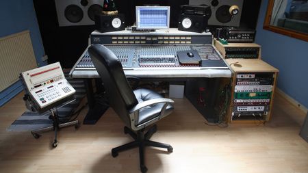 A studio chair in front of a mixing desk in a studio control room