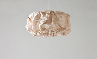 A white rock-shape/paper-style lamp shade hanging from above.