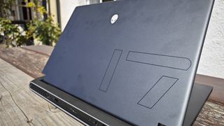 A dark grey Alienware m17 R5 gaming laptop sitting on a wooden table