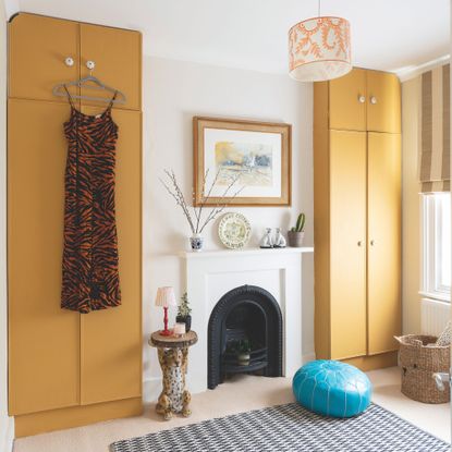 White painted room with yellow fitted wardrobes and a fireplace in between them