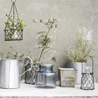 wire plant hanger with glass pot and silver colour wall