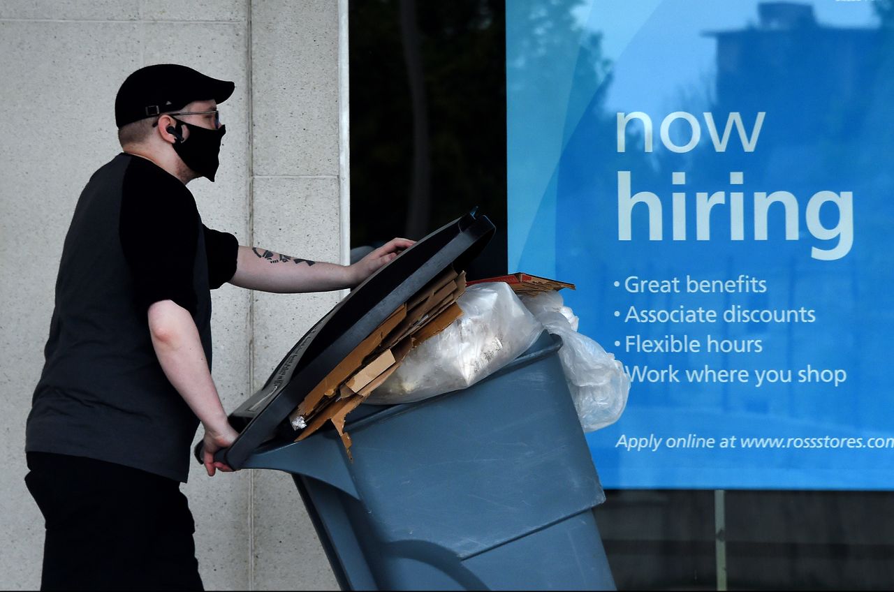 A person walks by a now hiring sign.