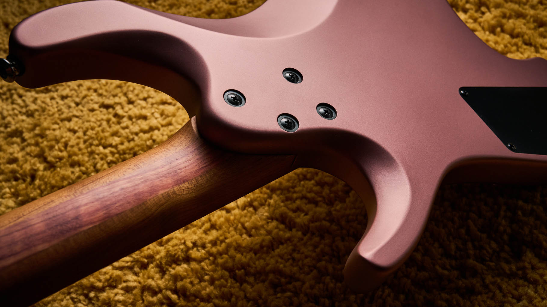 Ibanez Q54W: the headless electric guitar is finished in Copper Metallic Matte and photographed against a thick light-tan colored carpet.