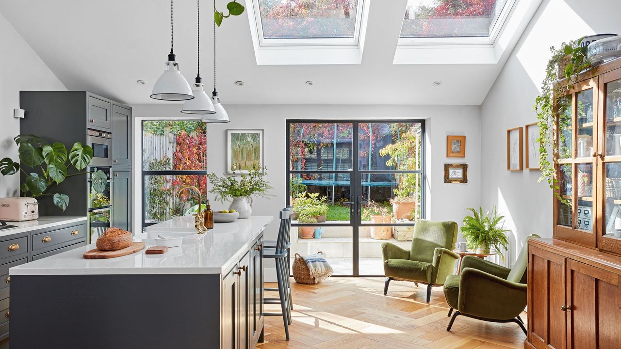 Kitchen and lounge area with blue units and island and green retro chairs