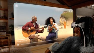 A woman wearing an Apple Vision Pro headset while watching a spatial video of two people playing guitar on the beach