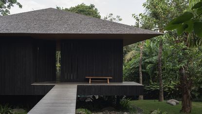 tsuki, a house in bali with pitched roof and natural materials set in lush tropical greenery