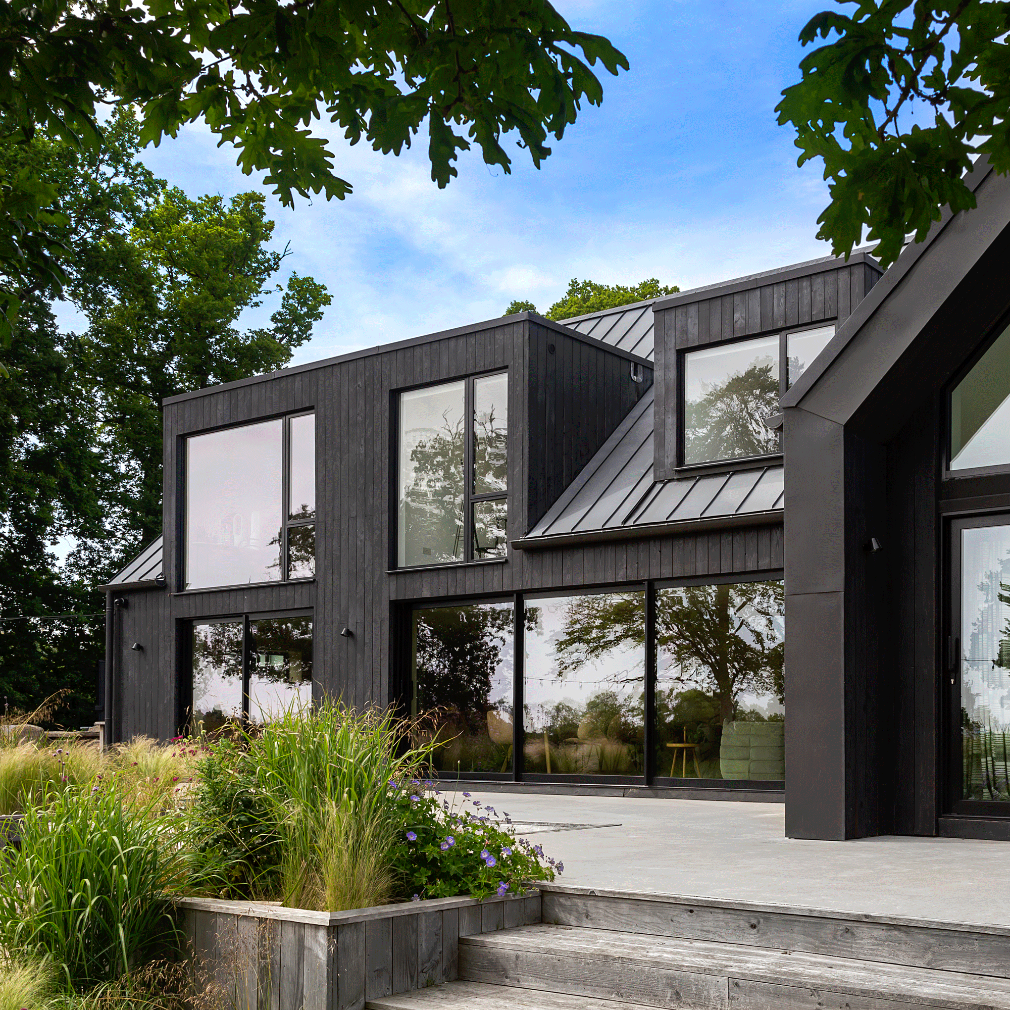 exterior of a modern new build house with black timber cladding and striking architectural glazing