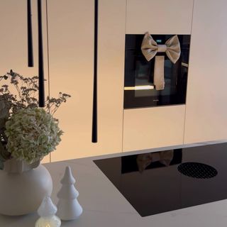 A modern kitchen with a vase of flowers and a tea towel hanging on the oven door tied into the shape of a bow