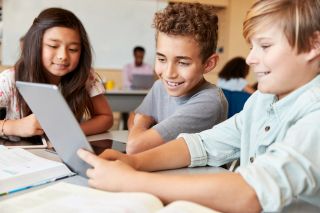 Elementary school boys using tablet computer in school class