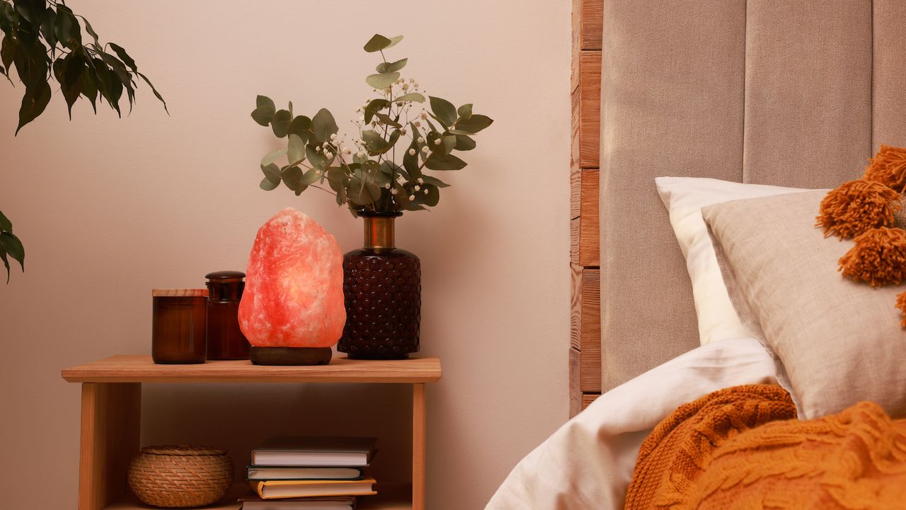 Beautiful Himalayan salt lamp and eucalyptus branches on nightstand in bedroom