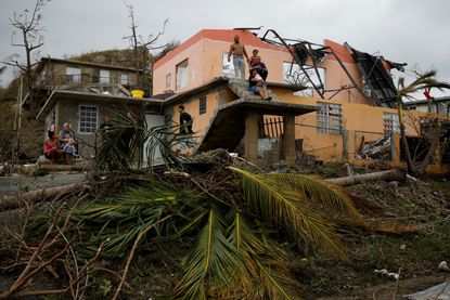 Residents sit outside a damaged home after Hurricane Maria.