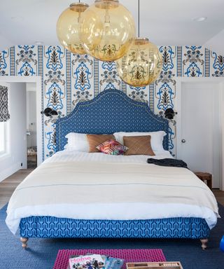 Box bedroom ideas illustrated by a patterned wallpaper and blue patterned headboard.