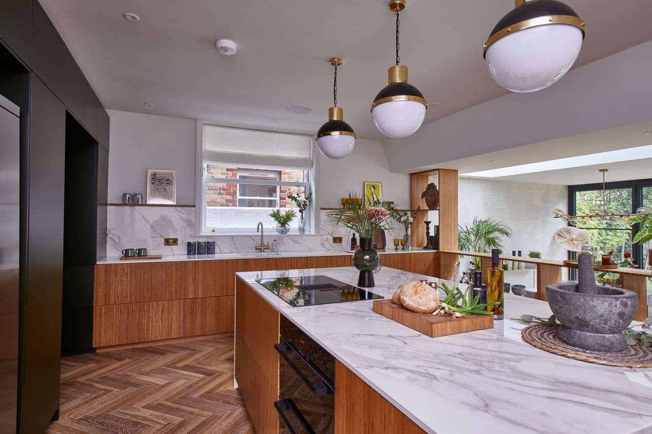 The kitchen has white marble worktops and wooden cabinets