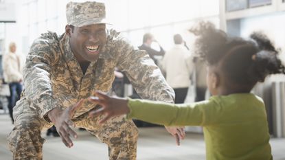 A military veteran opens his arms to a child running toward him. 