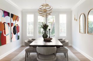 dining room with bold artwork wooden table and upholstered dining chairs with french windows and mirrors