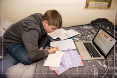 teenage boy sat on bed studying for GCSE exams