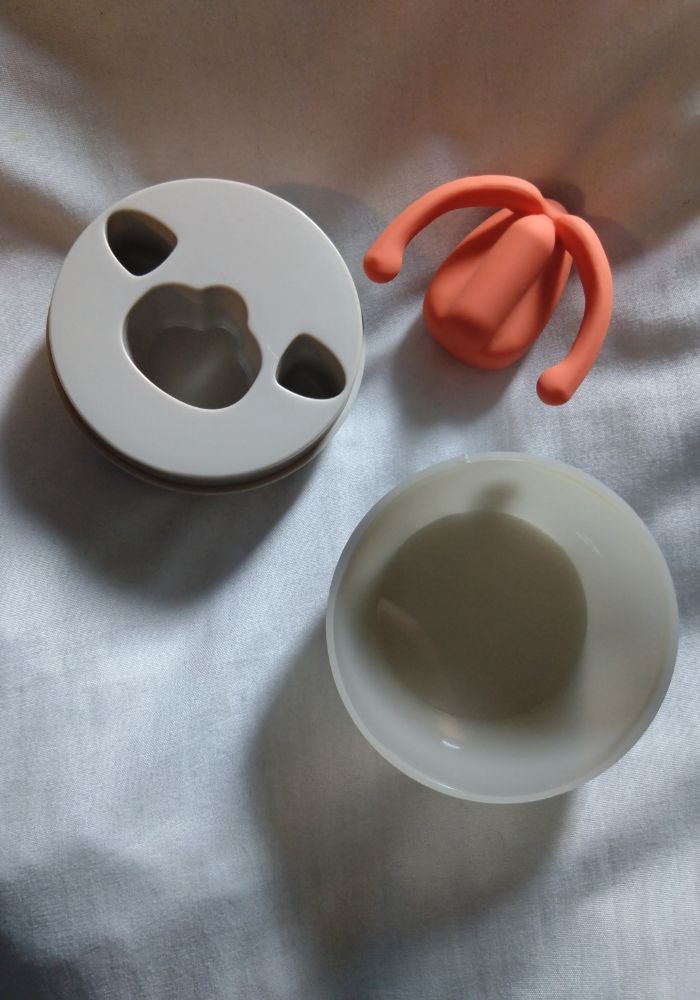 Dame Eva review image by Ness Cooper Dame Eva in peach with charging and storage case on white bedding