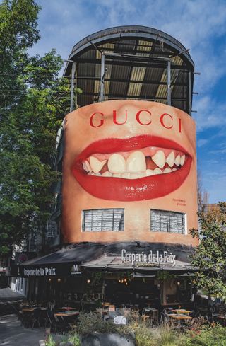 billboard displaying smiling red lips is situated above a cafe