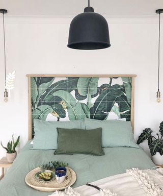 A DIY headboard in bedroom using green palm print wallpaper wall decor with black ceiling lighting decor