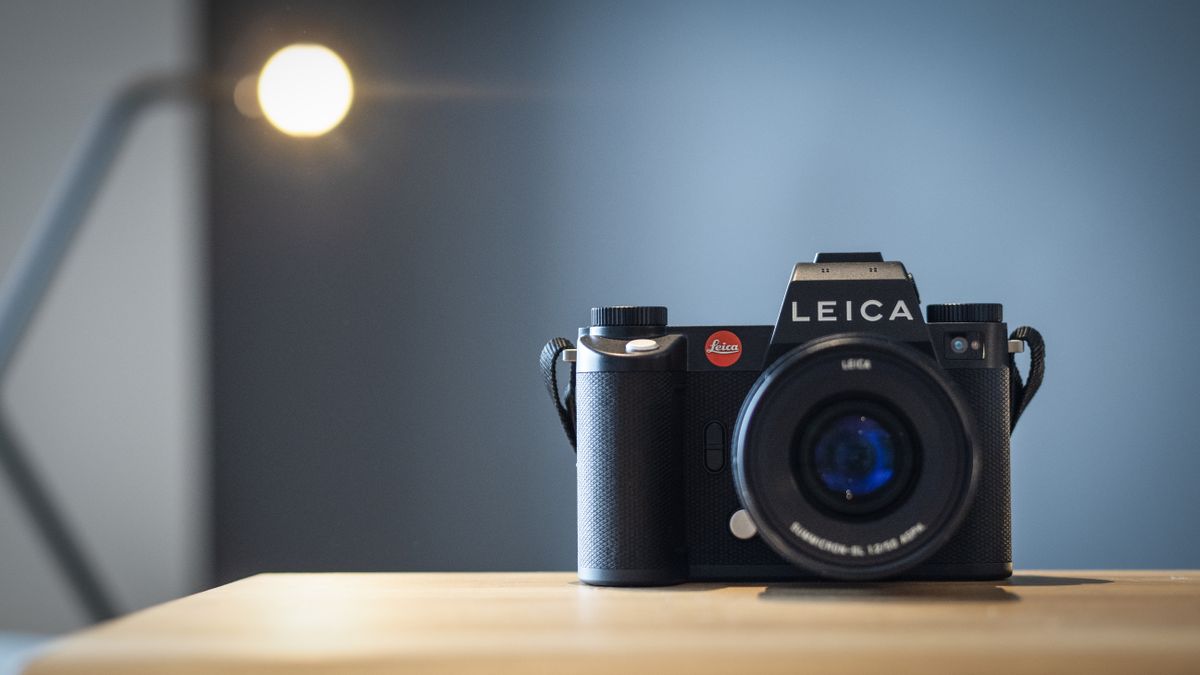 Leica SL3 camera on a wooden surface against a blue background