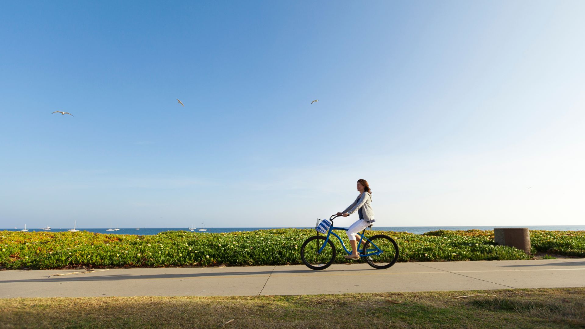 Woman riding bike along seaside path