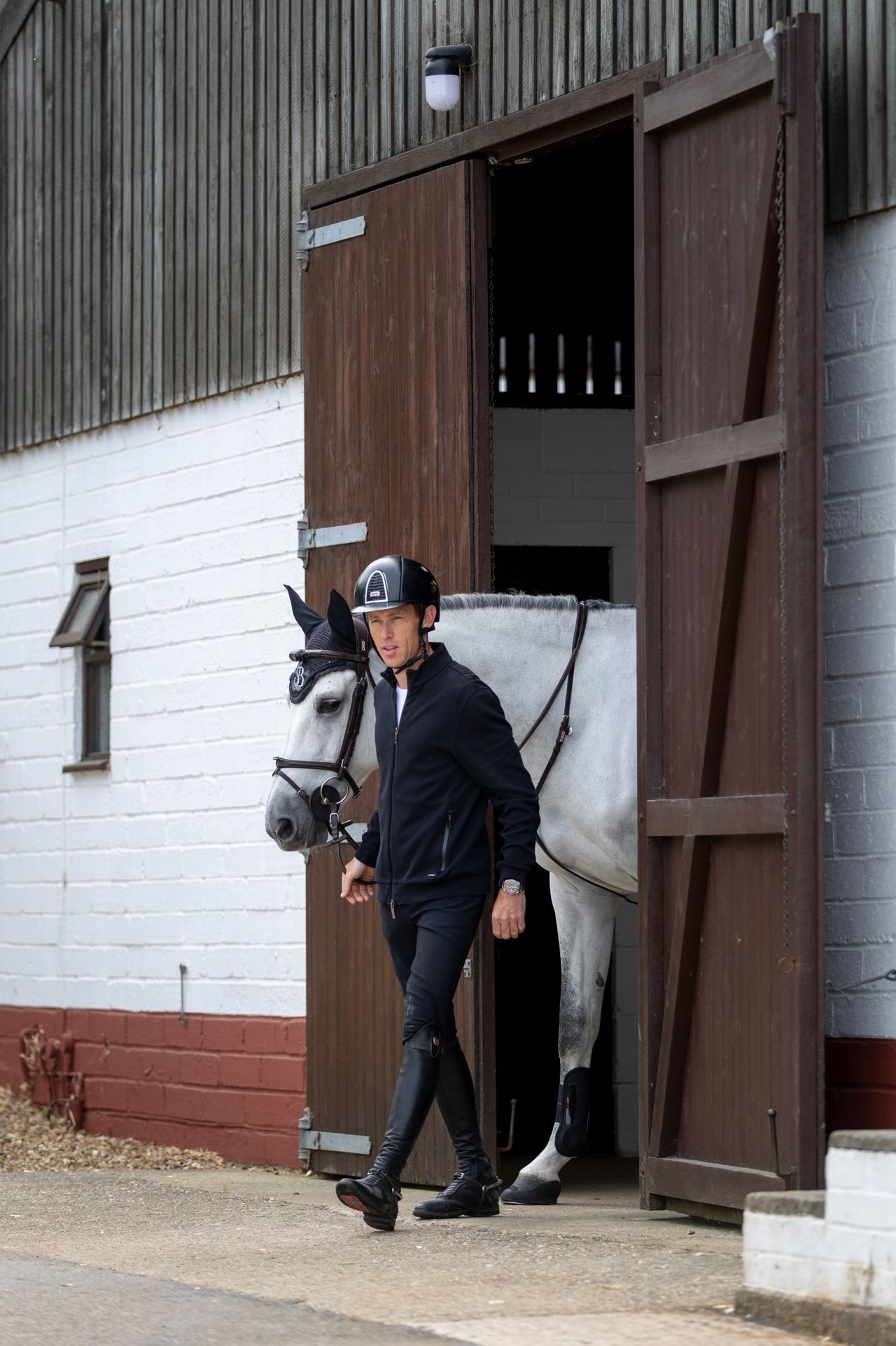 Scott Brash leads a white horse called Hello Mango out of its stables