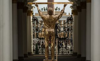 A 'golden man' holding a level above his head.