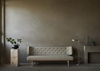 A beige/brown wall with matching sofa and marble plinth displaying a plant