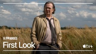 Image of Gary Oldman as Jackson Lamb standing in a meadow surrounded by tall grass. Copy on image reads: Slow Horses First Look."