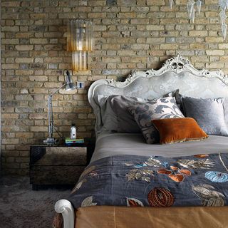 bedroom with teaming brick walls with embroidered linen bed and wall light