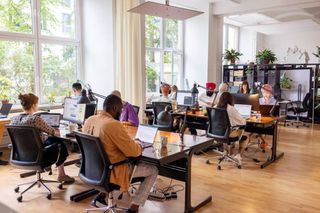 Busy office with workers at desks working.