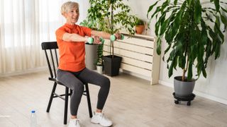 a senior woman lifting dumbbells from a chair