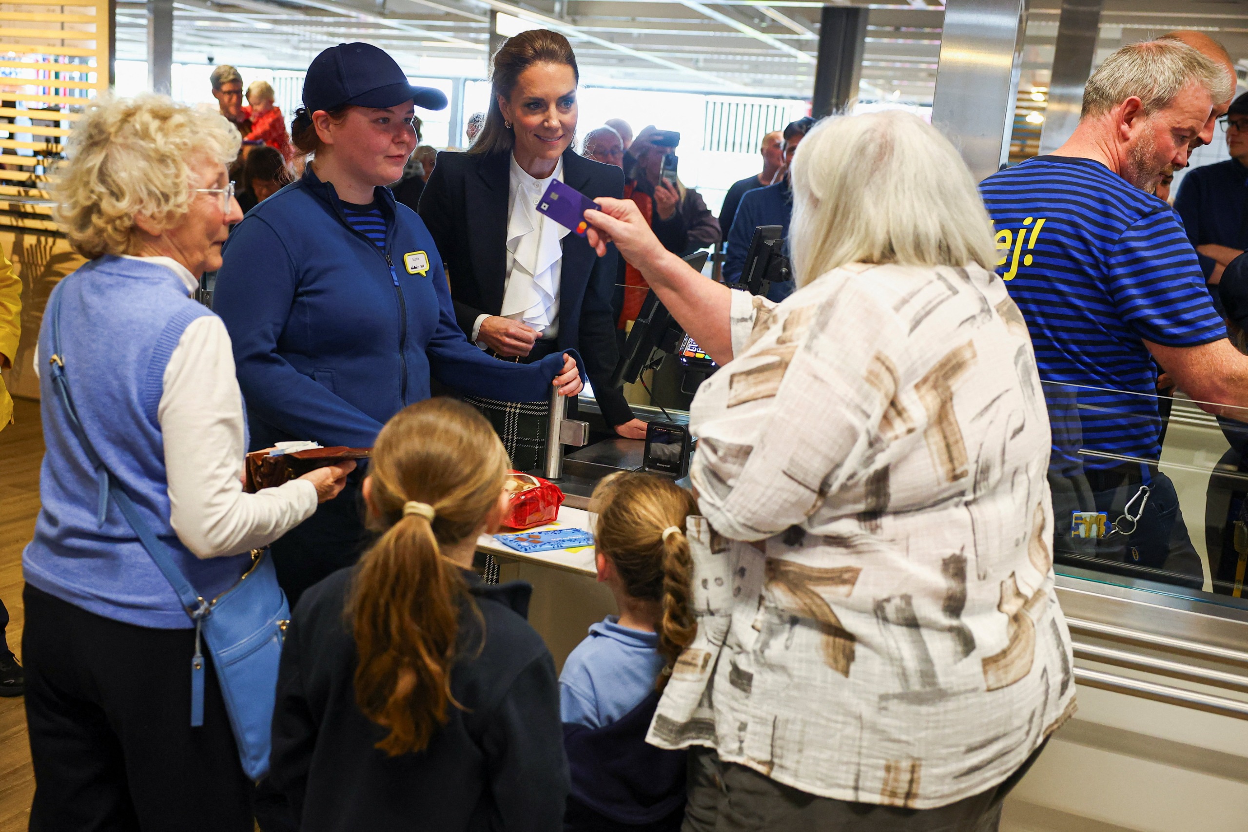 Princess Kate working at an Ikea register as a woman hands her credit card