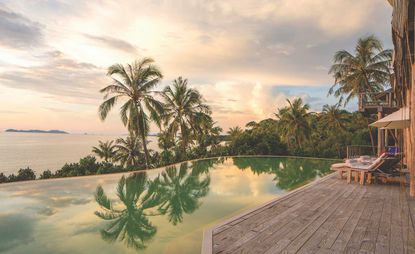 Soneva Kiri exterior view of pool, palm trees and ocean