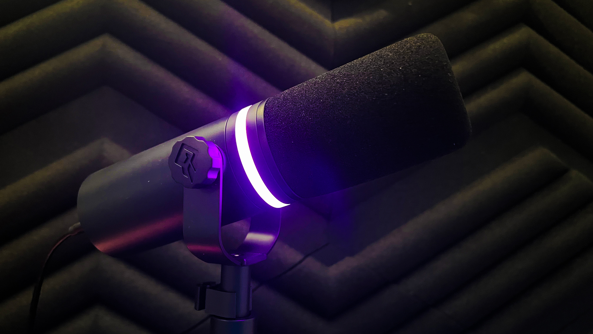 BEACN Mic review image in front of a soundproof wall with the RGB light at full brightness coloured in pink.
