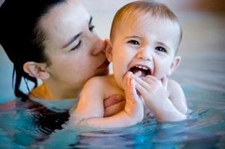 Mother swimming with her baby