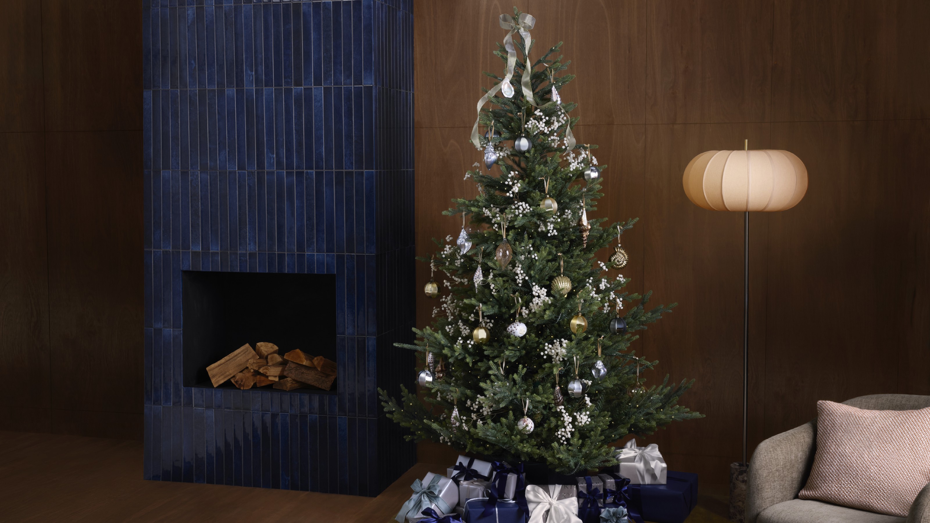 A living room with a decorated Christmas tree decorated with baubles from The Connoisseur theme at John Lewis