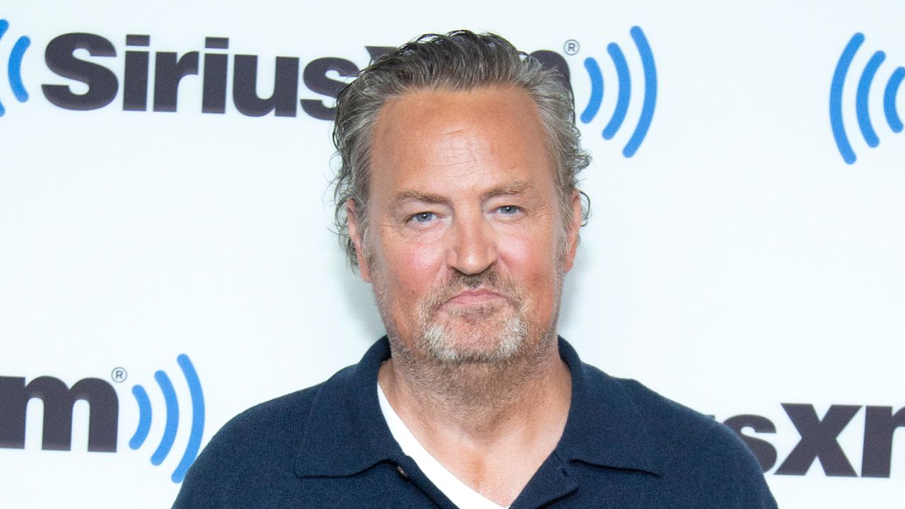 Matthew Perry has gray hair and a beard and wears a navy shirt to visit SiriusXM Studios on November 01, 2022