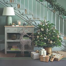A hallway with a staircase and a decorated small Christmas tree