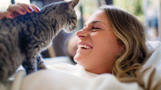 Woman smiling at cat on her chest