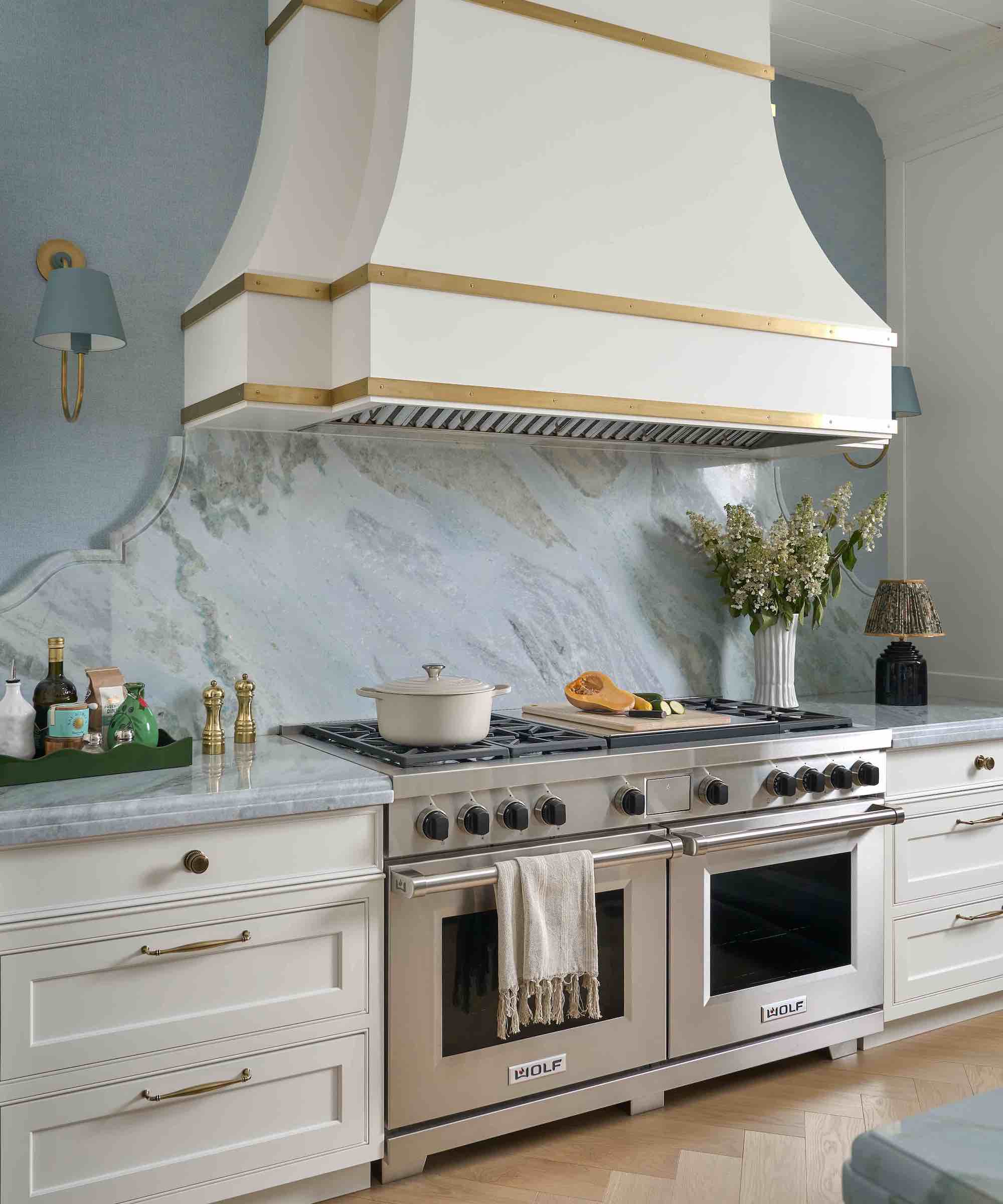 white kitchen with marble backsplash and steel range and outside extractor
