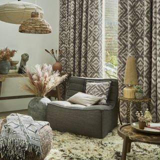 A boho chic style living room with lots of geometric patterned soft furnishings, including grey patterned curtains