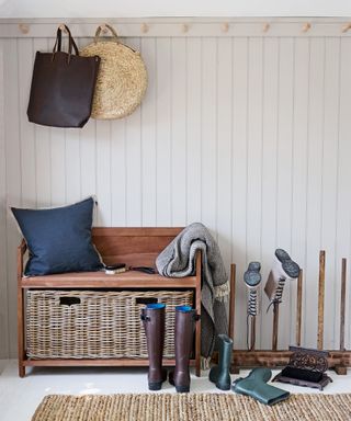 A mudroom with a boot bench featuring a deep woven basket under the seat