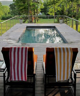 A pool on a decked terrace overlooking a woodland