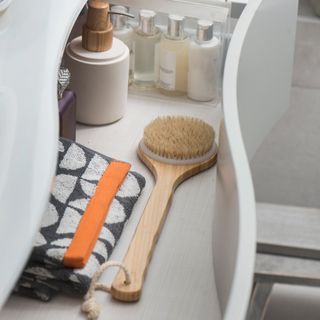 A close-up shot of the inside of a grey vanity unit with various cosmetic and beauty products including body brush