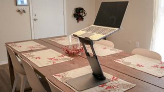 A laptop on a laptop stand at a kitchen table