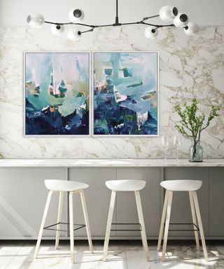 white bar stools and breakfast bar against wall with blue and white abstract artwork above